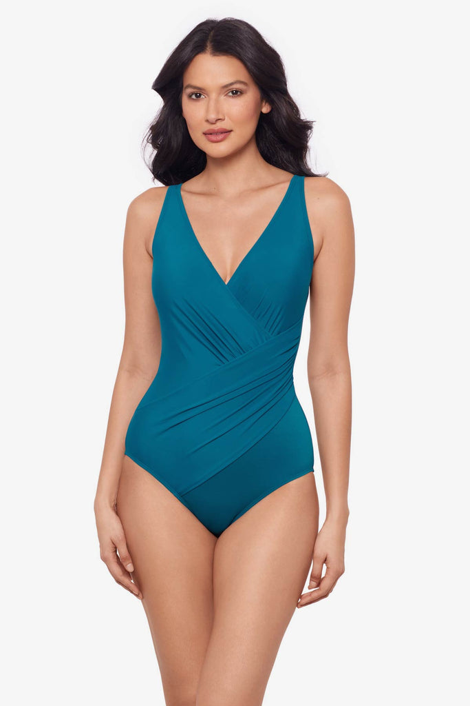 Woman wearing an aegean blue one-piece swimsuit with wrap detail