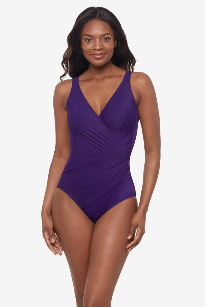 Woman wearing a mulberry purple one-piece swimsuit with wrap detail 