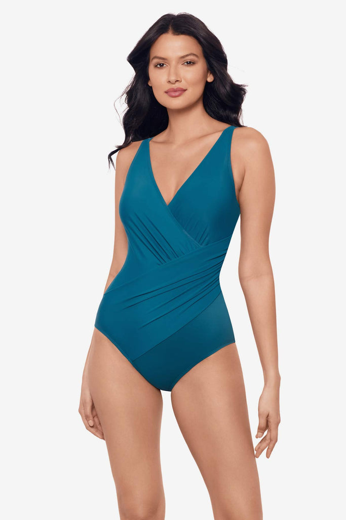 Woman wearing an aegean blue one-piece swimsuit with wrap detail 