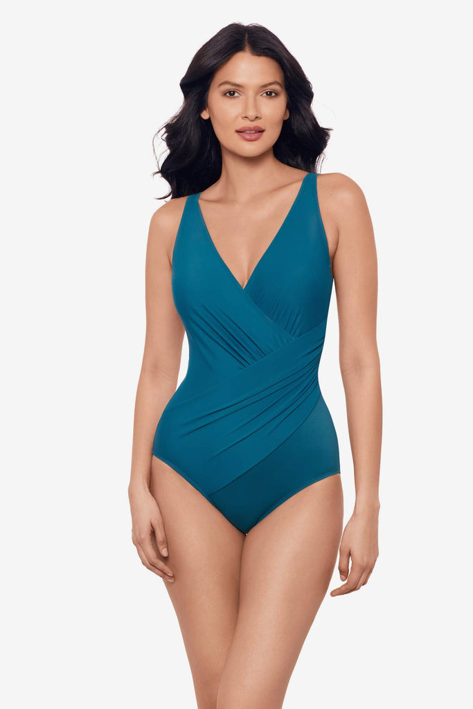 Woman wearing an aegean blue one-piece swimsuit with wrap detail 