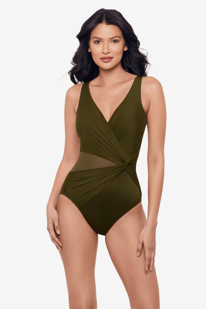 Woman wearing a nori green one-piece swimsuit with a mesh cut out on the left side 