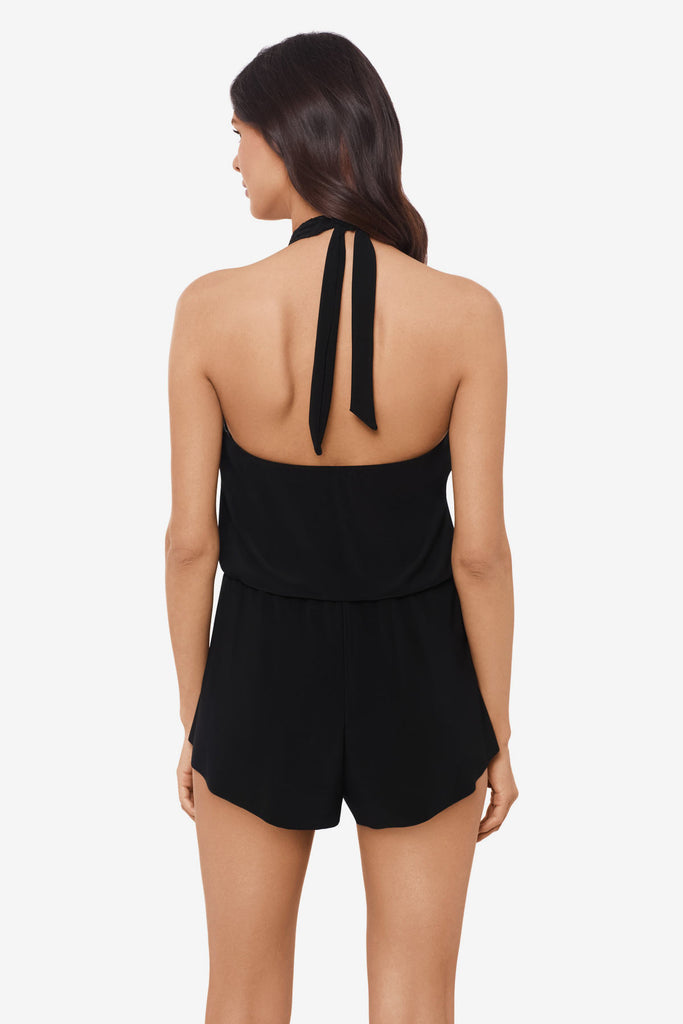 Woman facing away wearing a black swim romper with a high neckline