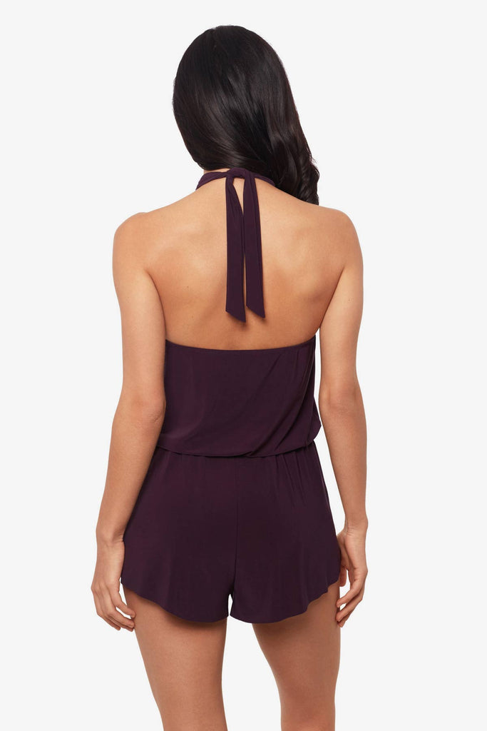 Woman facing away wearing a prune purple swim romper