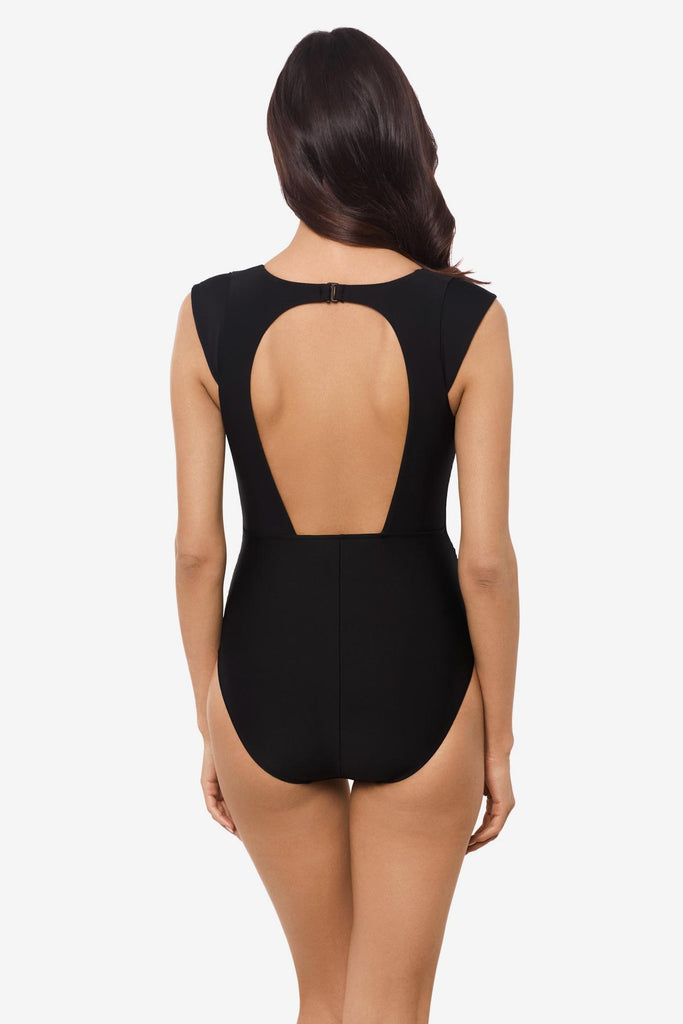 Woman facing away wearing a black one-piece swimsuit with a cut out back