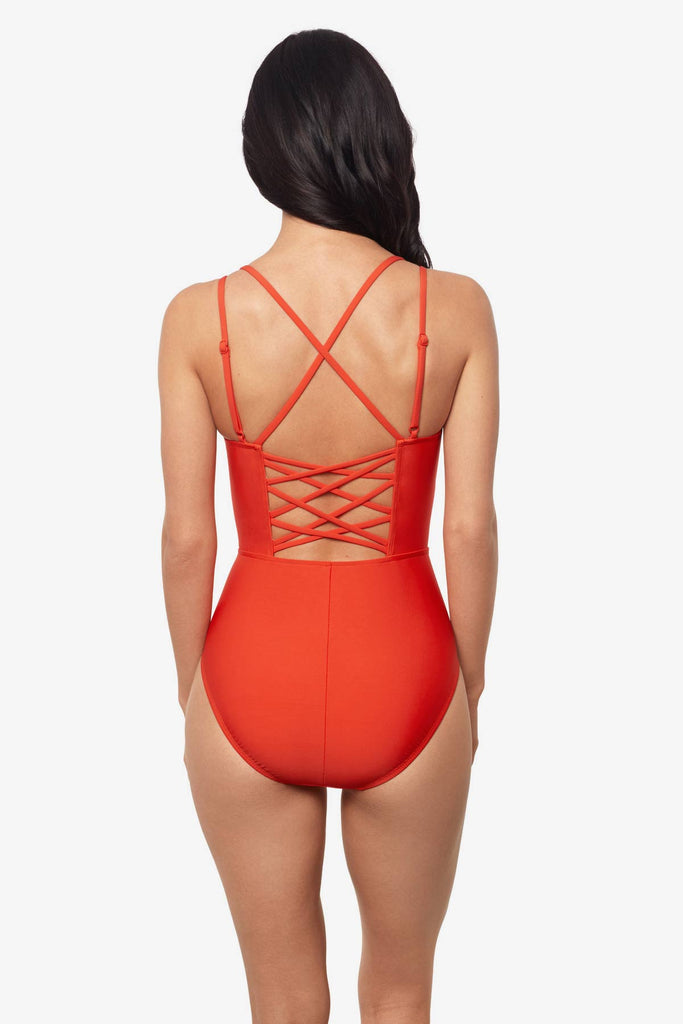 Woman facing away wearing a blaze orange one-piece swimsuit with detailed straps