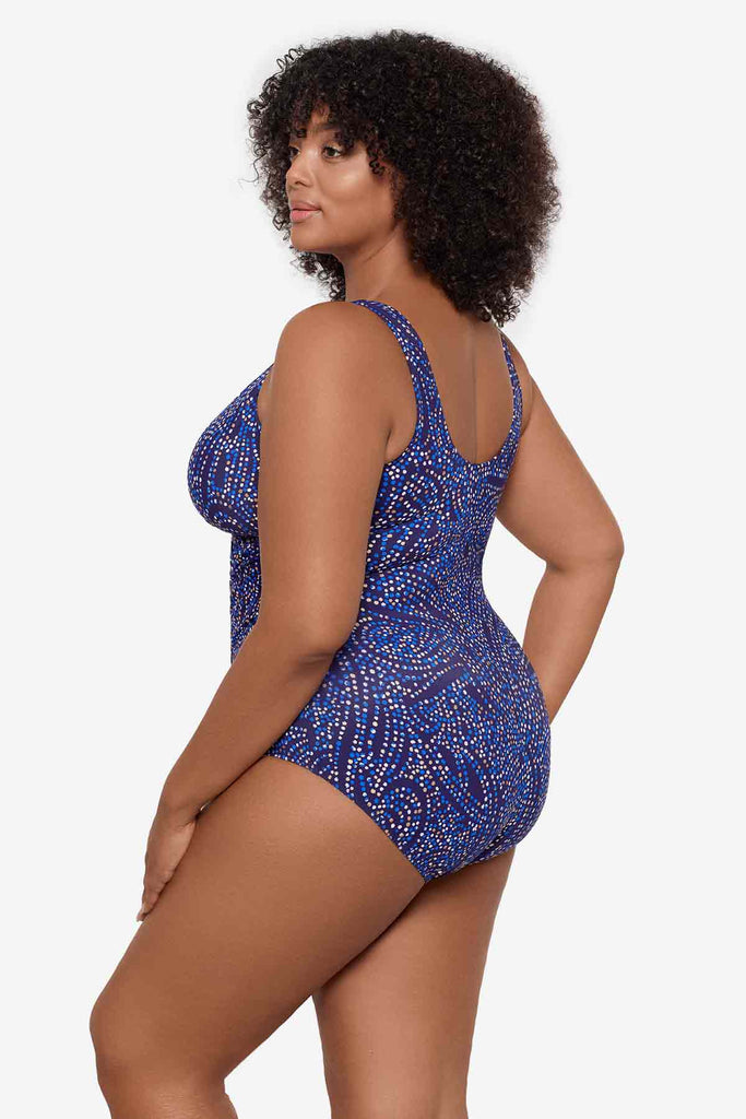 Woman facing left to show detail of one-piece swimsuit