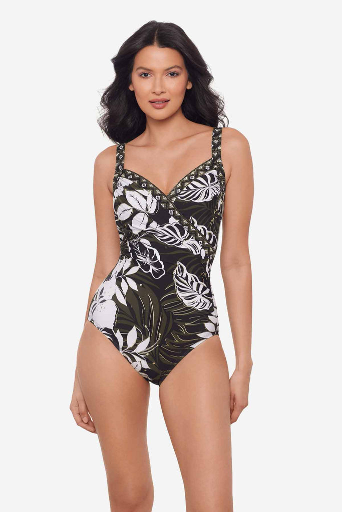 Woman wearing a multicolor one-piece swimsuit with large white palm leaves