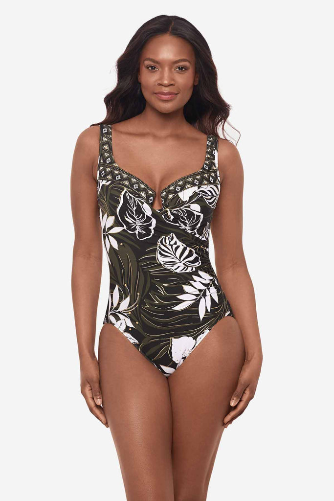 Woman wearing a multicolor one-piece swimsuit with large white palm leaves