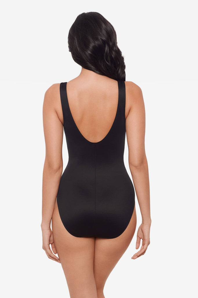 Woman facing away wearing an all-black one-piece swimsuit 