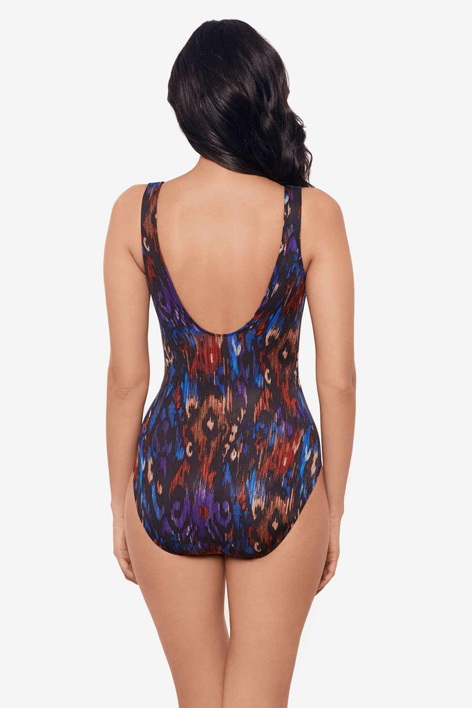 Woman turned away wearing a one-piece swimsuit with a multicolor abstract pattern