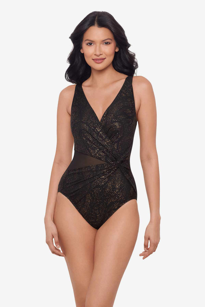 Woman wearing a black shimmery one-piece swimsuit with mesh cut out on left side