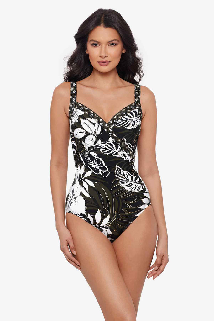 Woman wearing a multicolor one-piece swimsuit with large white palm leaves