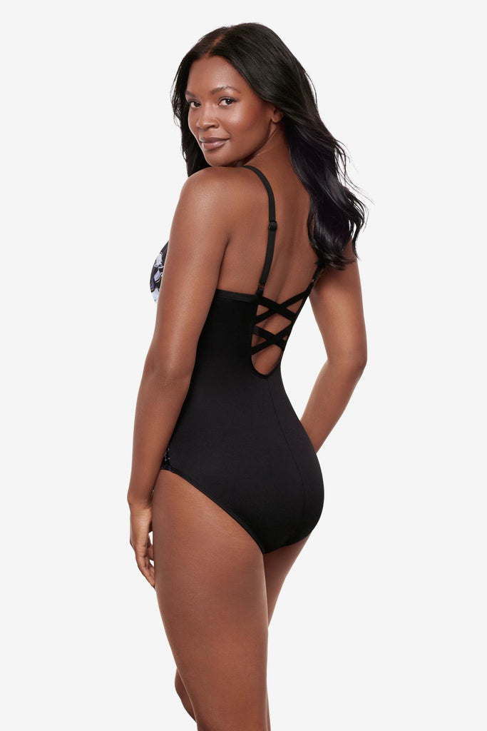 Woman turned left wearing a black and white floral printed one-piece swimsuit with the design on each side