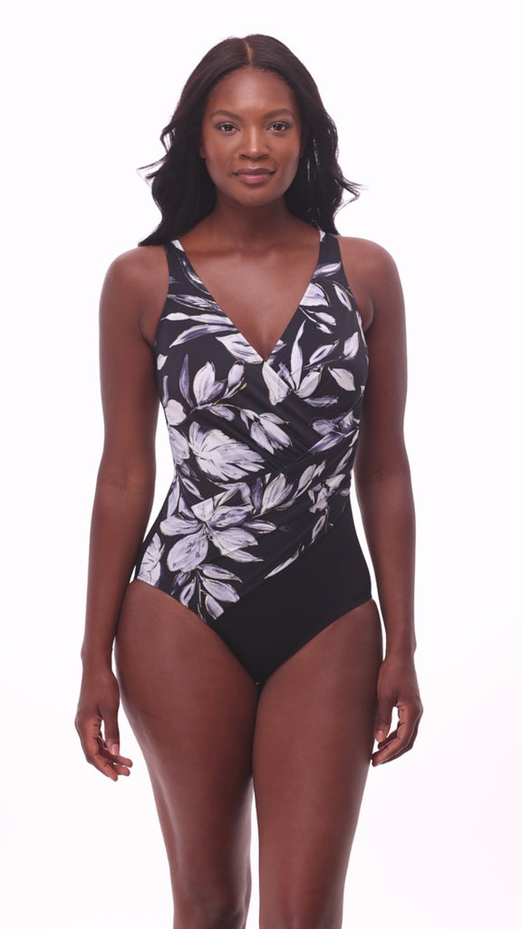 Woman wearing a black and white floral printed one-piece swimsuit with a V neckline